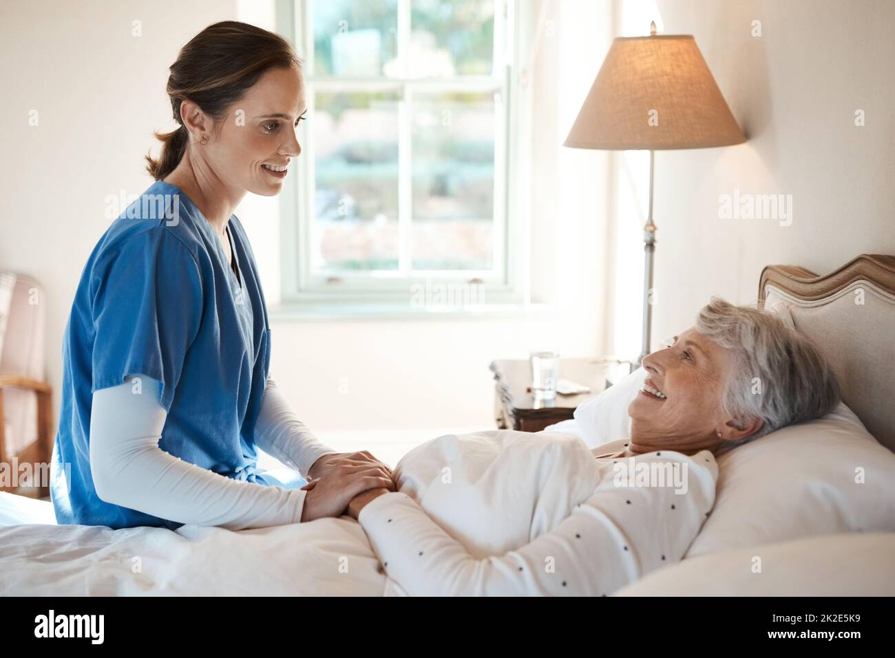 Se sei a tuo agio, sono felice. Shot di una giovane infermiera che chiacchierava con una donna anziana a letto in una casa di riposo. Foto Stock