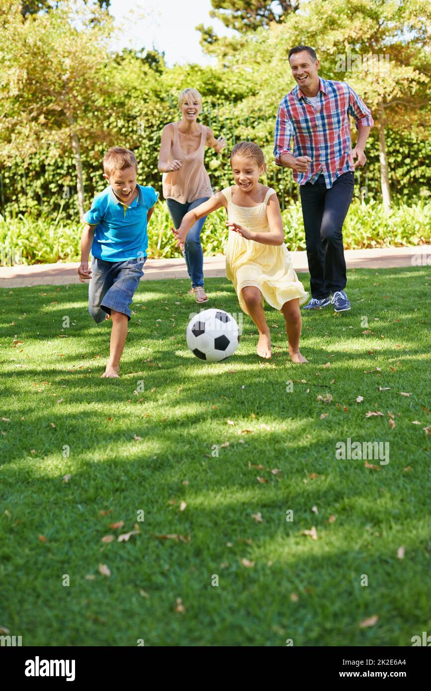 Divertimento per tutta la famiglia al parco. Una famiglia felice che gioca a calcio nel parco in una bella giornata estiva. Foto Stock