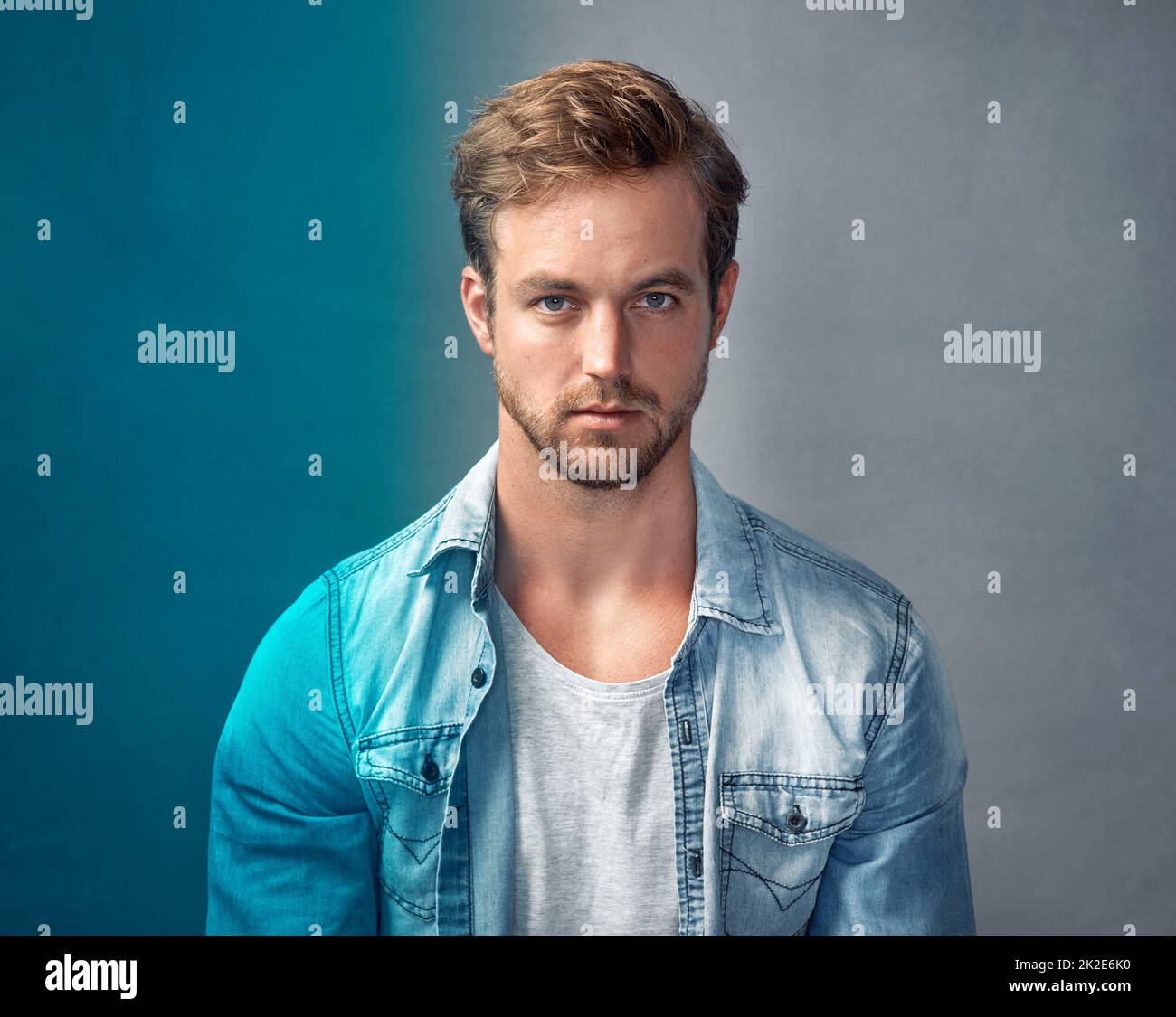 Vivete la vostra vita a colori. Ritratto di un bel giovane uomo con una sovrapposizione blu che si posa su uno sfondo grigio in studio. Foto Stock