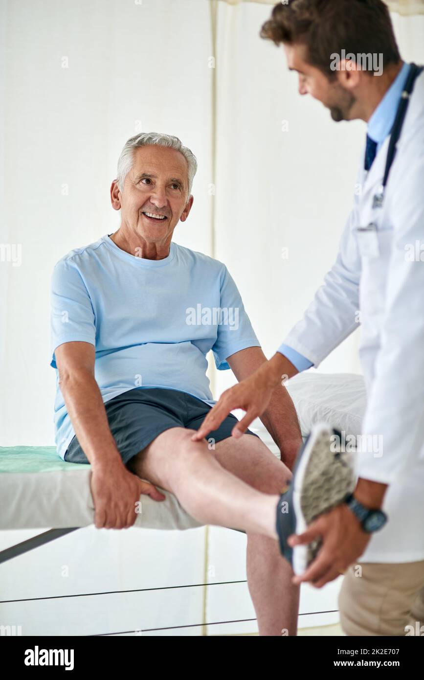 I suoi check-up sono sempre divertenti con il suo medico amichevole. Scatto corto di un uomo anziano felice che frequenta un controllo del ginocchio con un medico. Foto Stock