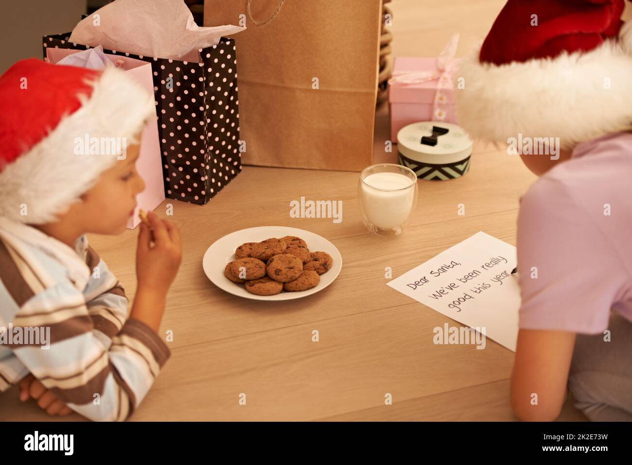 Sperando Babbo Natale piacerà i biscotti. Scatto corto di un fratello giovane e sorella che scrive una lettera a Babbo Natale. Foto Stock