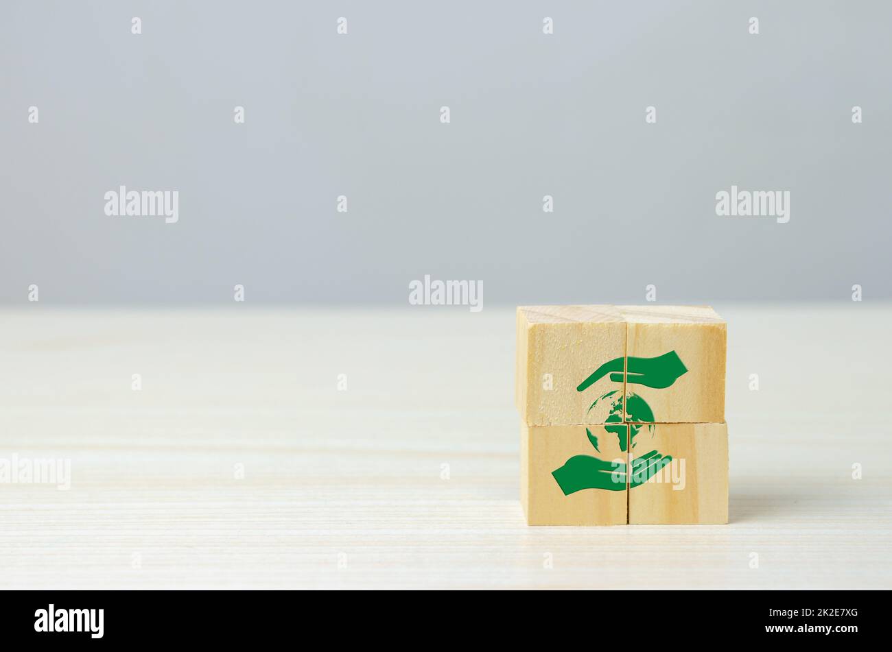 Cubo di legno con mano e globo icona netto zero. Concetto di business e sviluppo ecocompatibile in background. Foto Stock