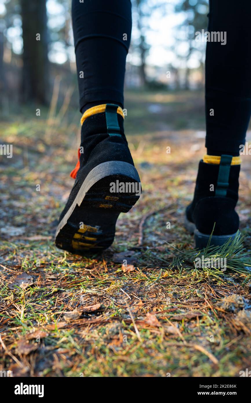 La ragazza cammina attraverso la foresta, primo piano di scarpe sullo sfondo della foresta. Concetto di viaggio, trekking ed escursionismo. Foto Stock