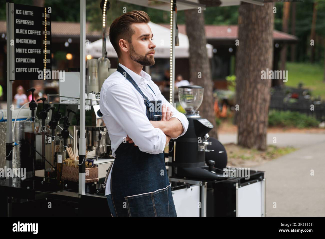 Bel barista uomo durante il lavoro nella sua caffetteria di strada Foto Stock