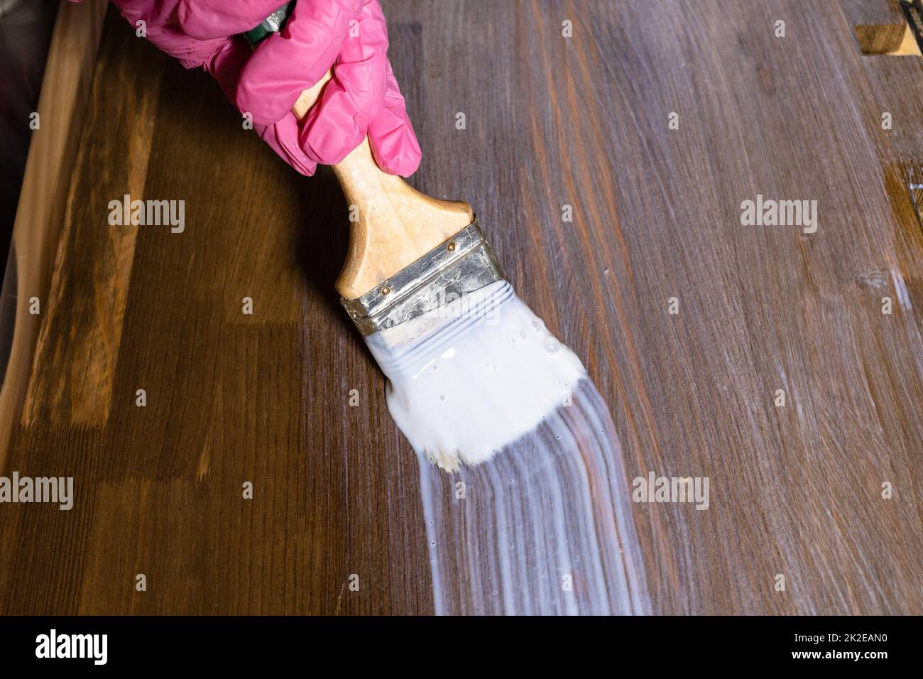 la mano gloved vernicia un asse di legno macchiato Foto Stock
