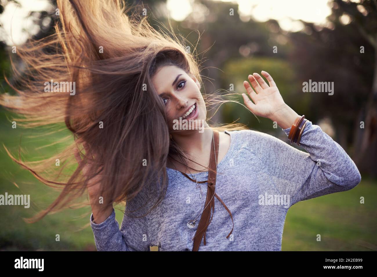 Questo è ciò che significa essere vivi. Ritratto di una bella giovane donna spensierata che scolpisce i capelli mentre all'aperto. Foto Stock