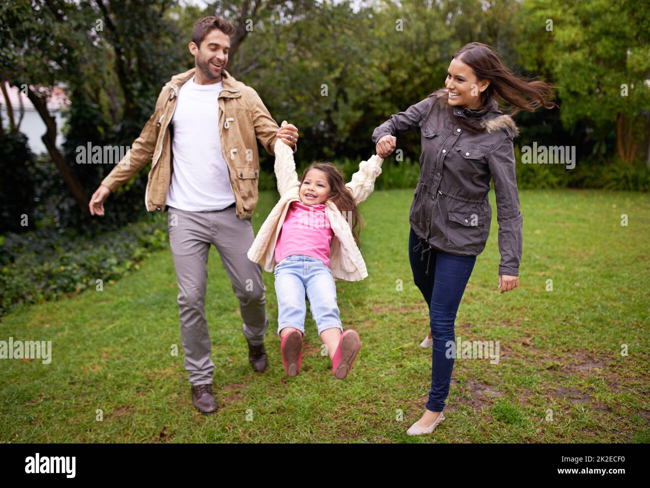 La famiglia è un piccolo mondo creato dall'amore. Un ritratto corto di due genitori felici con la loro figlia giovane in piedi all'aperto. Foto Stock