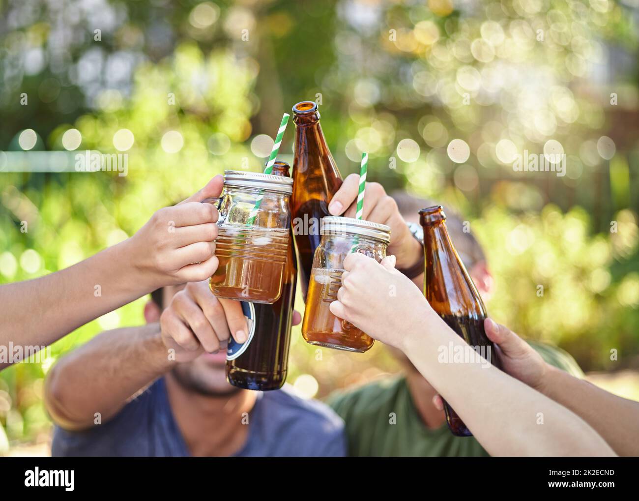 Grazie all'estate. Scatto corto di un giovane gruppo di amici che tostano mentre si gustano alcune bevande all'aperto al sole estivo. Foto Stock