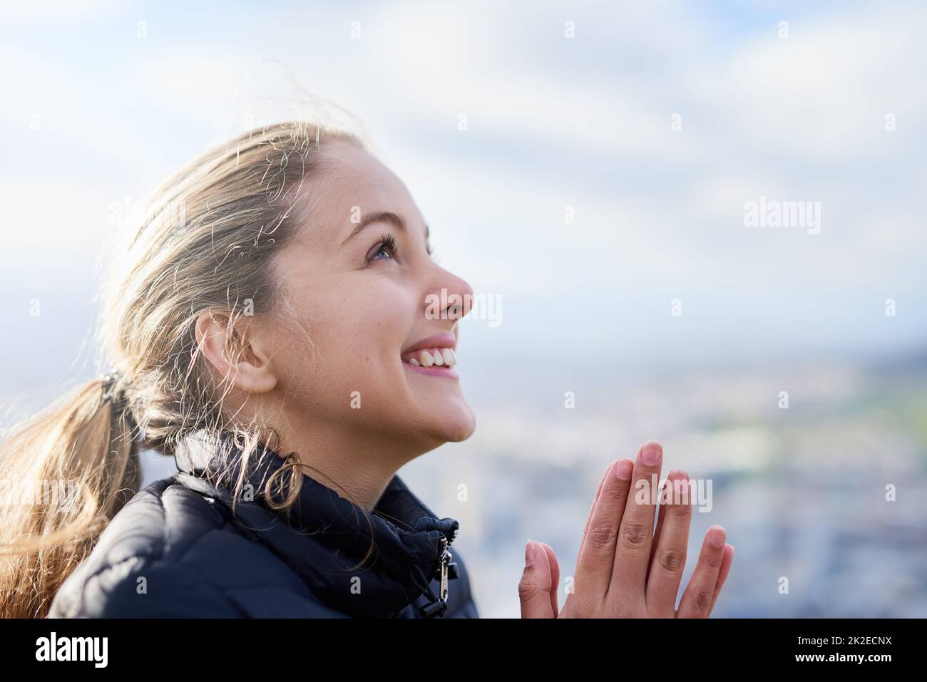 Grazie per le sue preghiere, alle quali è stata finalmente data risposta. Scatto corto di una giovane donna attraente in piedi con le sue mani insieme in preghiera fuori. Foto Stock