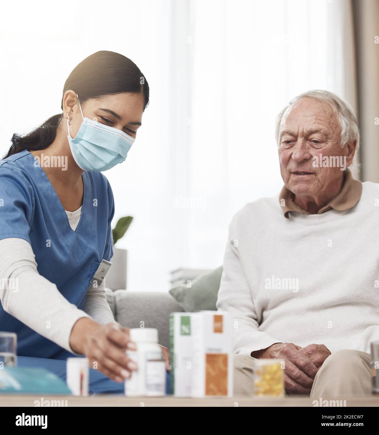 Quanti di questi prendono. Shot di una giovane infermiera femminile che aiuta un paziente con il suo farmaco durante un controllo a casa. Foto Stock