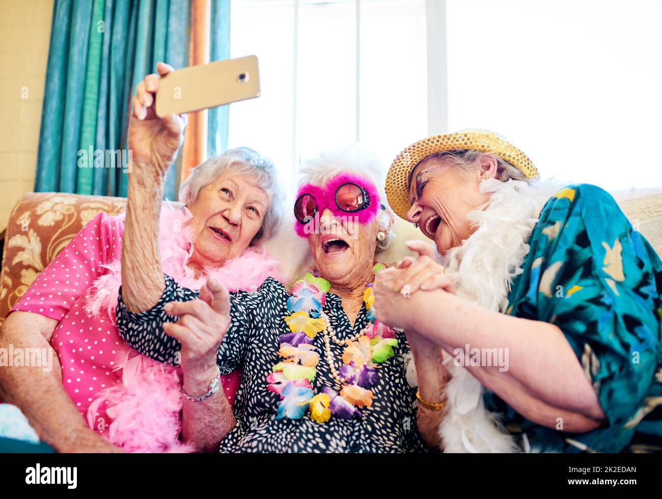 Come funziona questa cosa. Girato di un gruppo spensierato persone anziane indossando costumi funky e avvicinandosi per un selfie all'interno di un edificio. Foto Stock