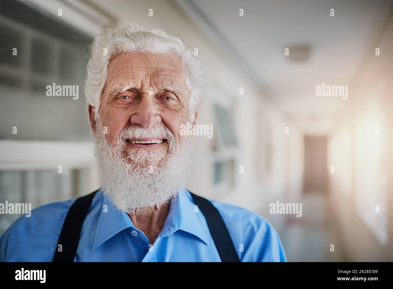 Pensionamento mi si adatta come un guanto. Ritratto di un uomo anziano felice che si posa nel corridoio della sua casa di cura. Foto Stock