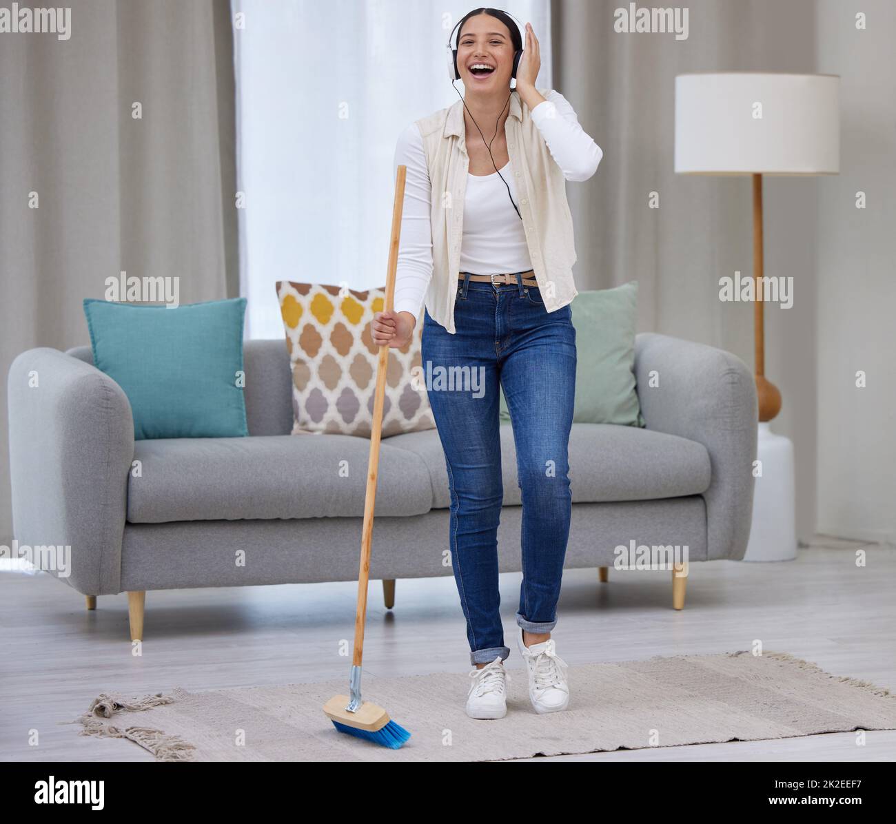 Rendi la pulizia la tua casa divertente. Scatto di una giovane donna che ascolta la musica mentre si spazzava il pavimento. Foto Stock