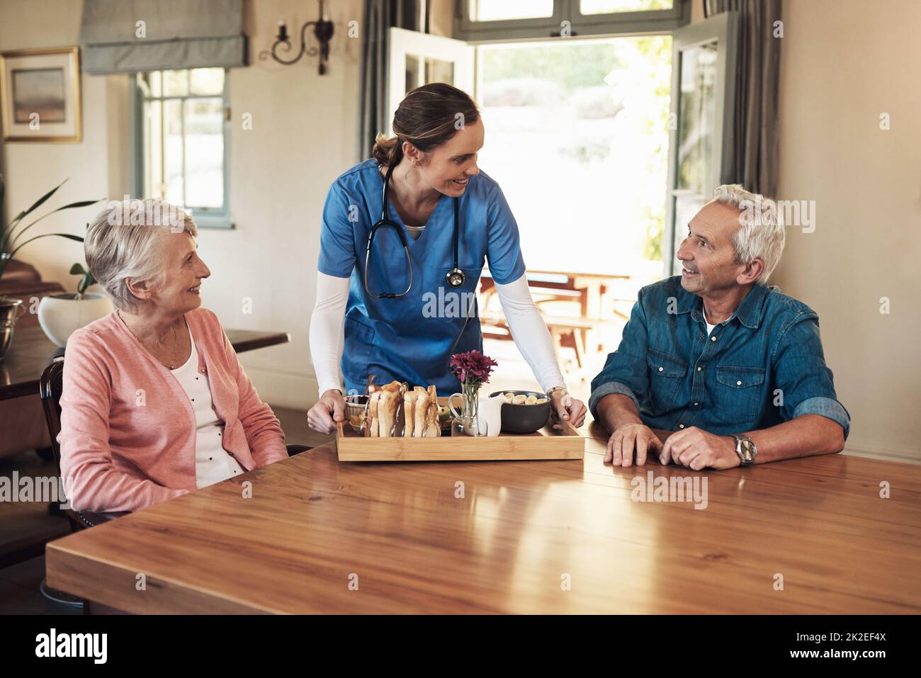 La migliore colazione è quella che si può fare insieme. Shot di una giovane infermiera che controlla su una coppia anziana durante la prima colazione in una casa di cura. Foto Stock