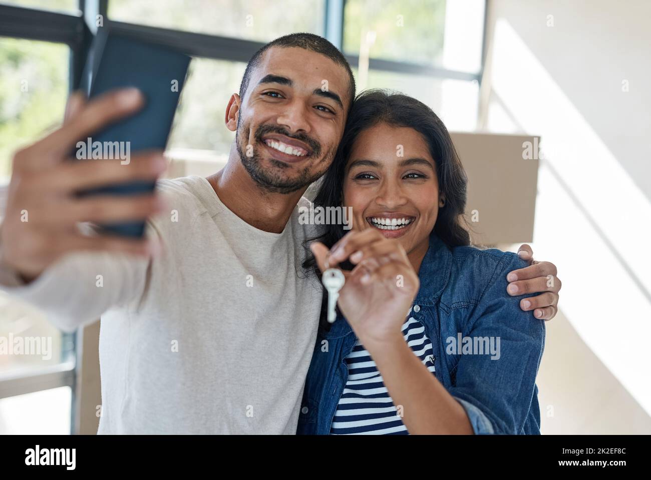 Questo è un momento che vale la pena catturare. Scatto di una giovane coppia felice prendendo un selfie mentre si spostano nella loro nuova casa insieme. Foto Stock