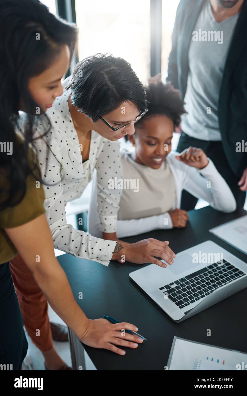 Date un'occhiata a questo.... Scatto corto di un gruppo di uomini d'affari riuniti intorno a un laptop in ufficio. Foto Stock