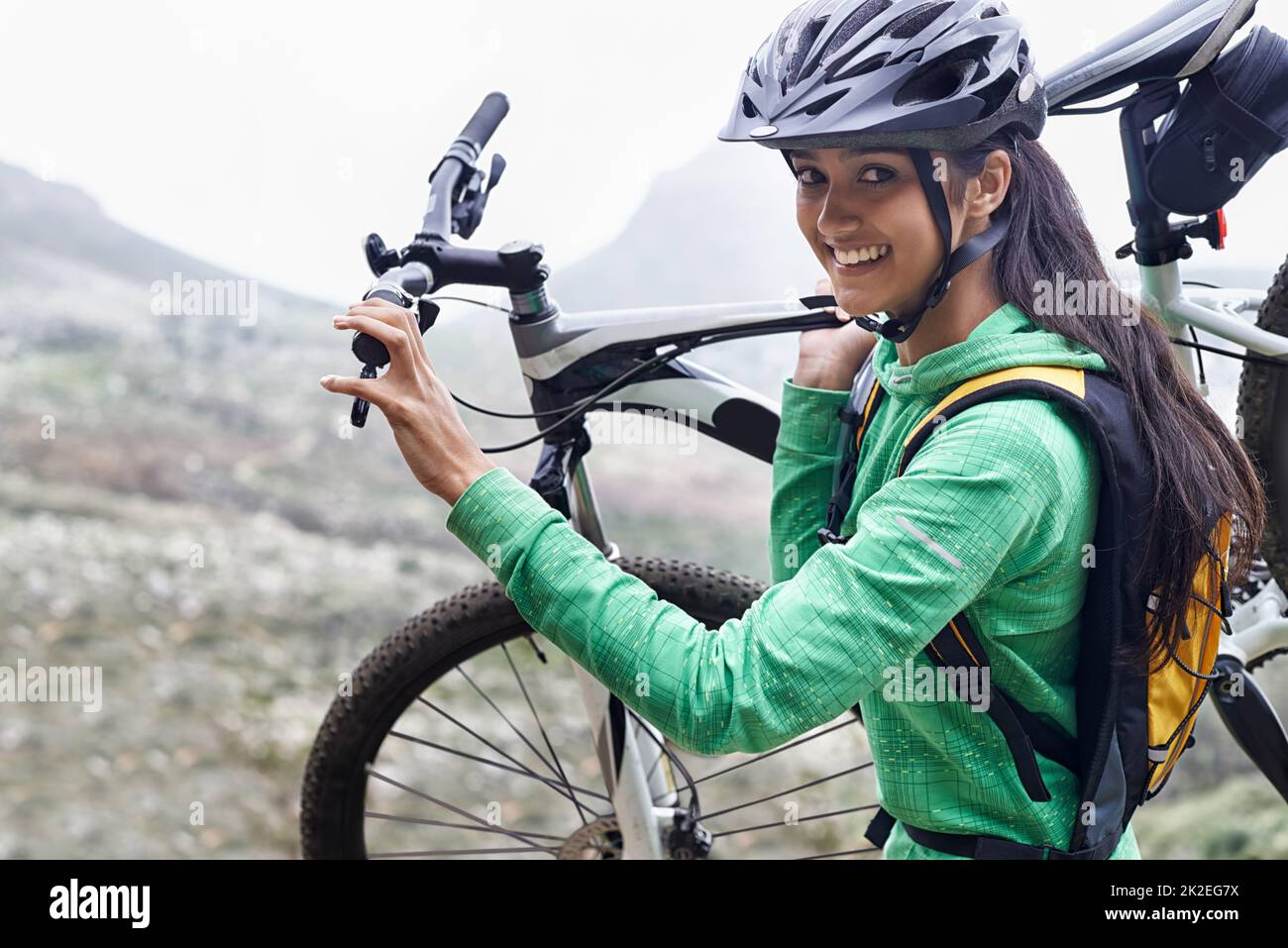 Sono un avventuriero. Una donna piuttosto giovane che porta la sua mountain bike. Foto Stock