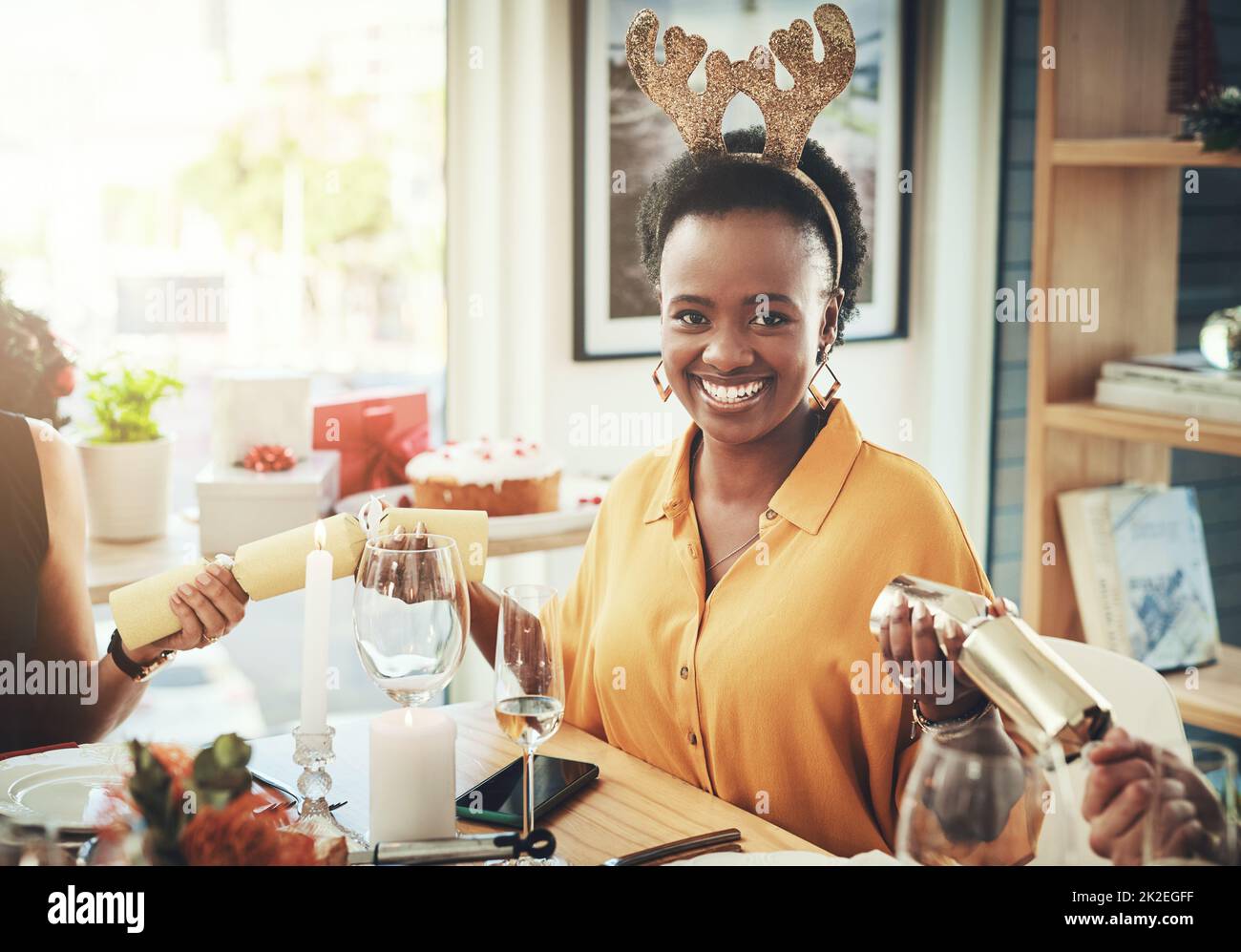 Questa è la parte più entusiasmante. Scatto corto di una giovane donna attraente che tira i cracker mentre si fa pranzo di Natale con i suoi amici a casa. Foto Stock