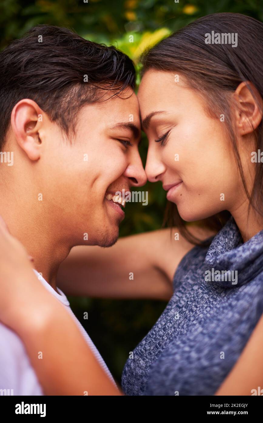 Hanno solo gli occhi l'uno per l'altro. Primo piano di una giovane coppia sorridente che abbraccia faccia a faccia all'esterno. Foto Stock