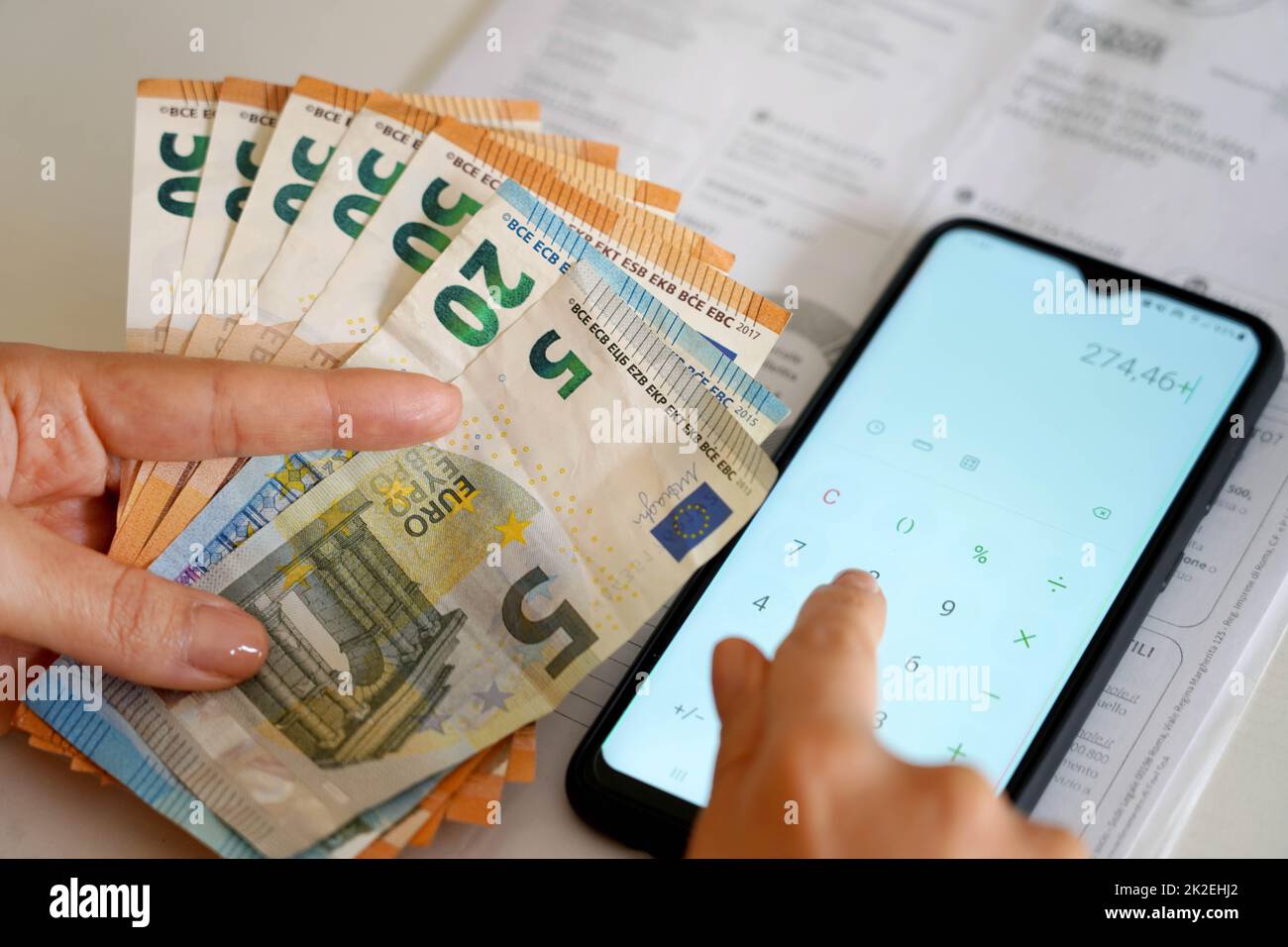 Aumento dei prezzi delle bollette energetiche durante la crisi finanziaria. Spese di conteggio manuale per l'uomo bolletta elettrica o bolletta del gas sulla calcolatrice per smartphone. Foto Stock