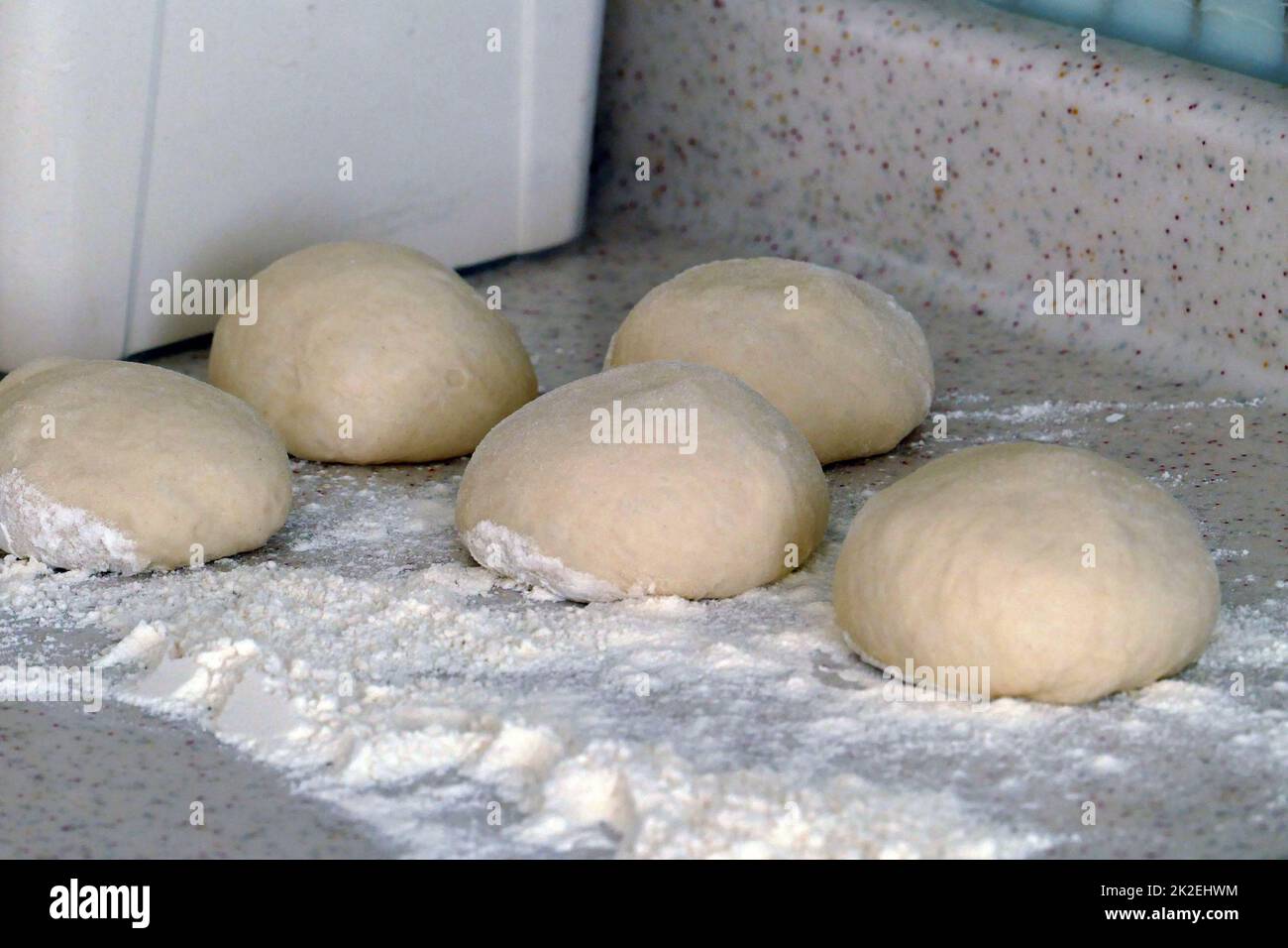 pezzi di pasta, una persona che arrotola l'impasto per fare ciambelle Foto Stock