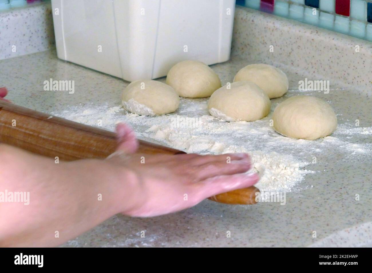 pezzi di pasta, una persona che arrotola l'impasto per fare ciambelle Foto Stock