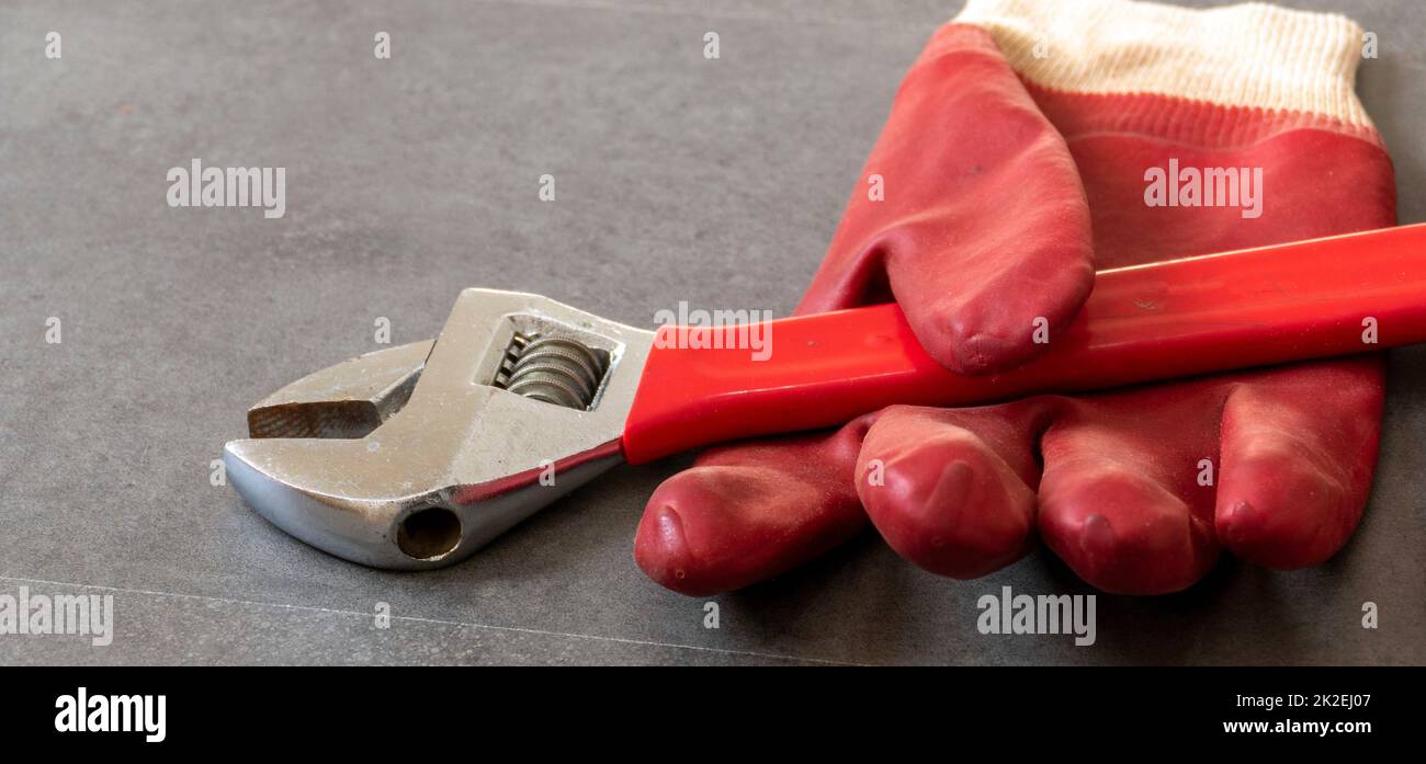 Per la sicurezza sul lavoro, è necessario lavorare con guanti, una chiave, guanti di plastica spessi sono in piedi su un pavimento Foto Stock