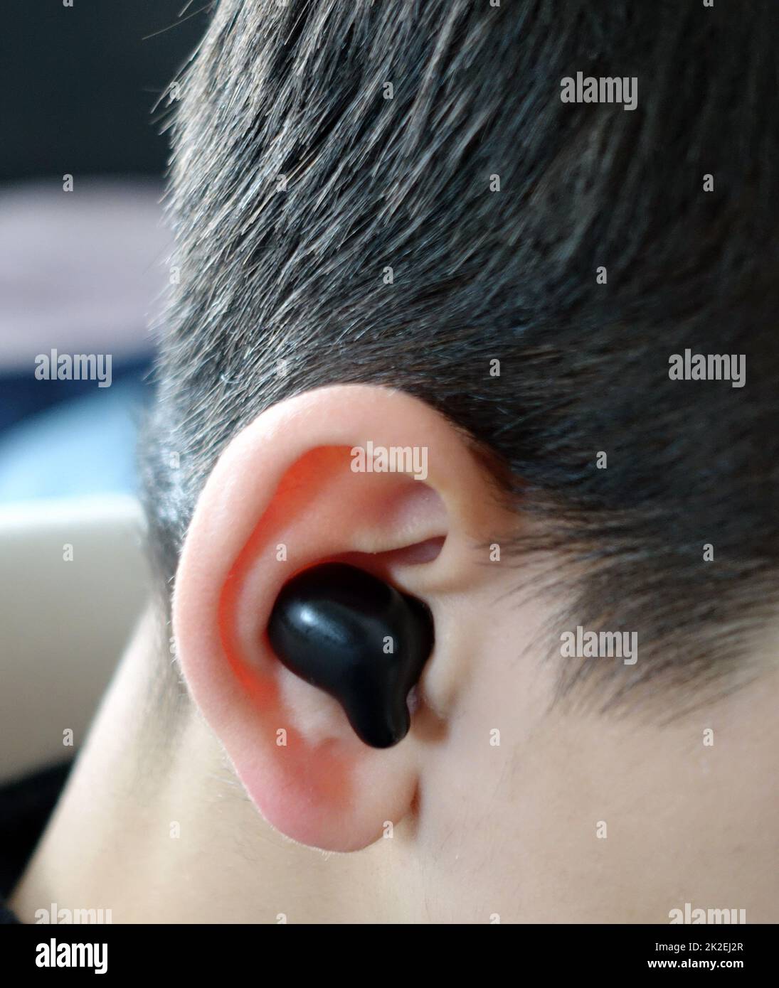 un adolescente ha un auricolare bluetooth nell'orecchio e sta ascoltando musica, auricolari e orecchie Foto Stock