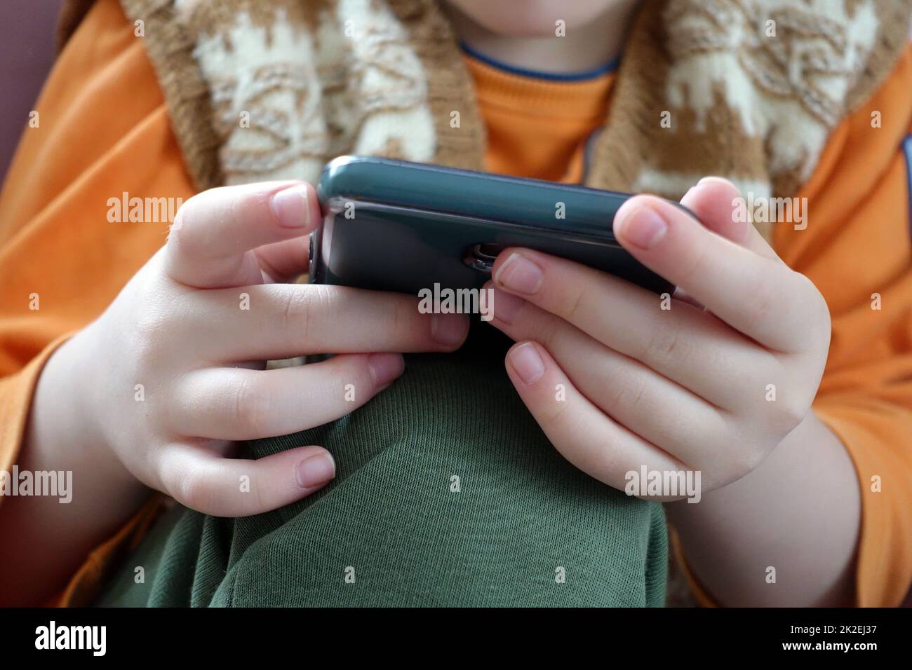 primo piano di un bambino che gioca con uno smartphone, primo piano della mano e del telefono cellulare Foto Stock