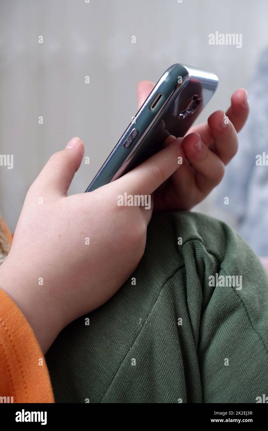 primo piano di un bambino che gioca con uno smartphone, primo piano della mano e del telefono cellulare Foto Stock