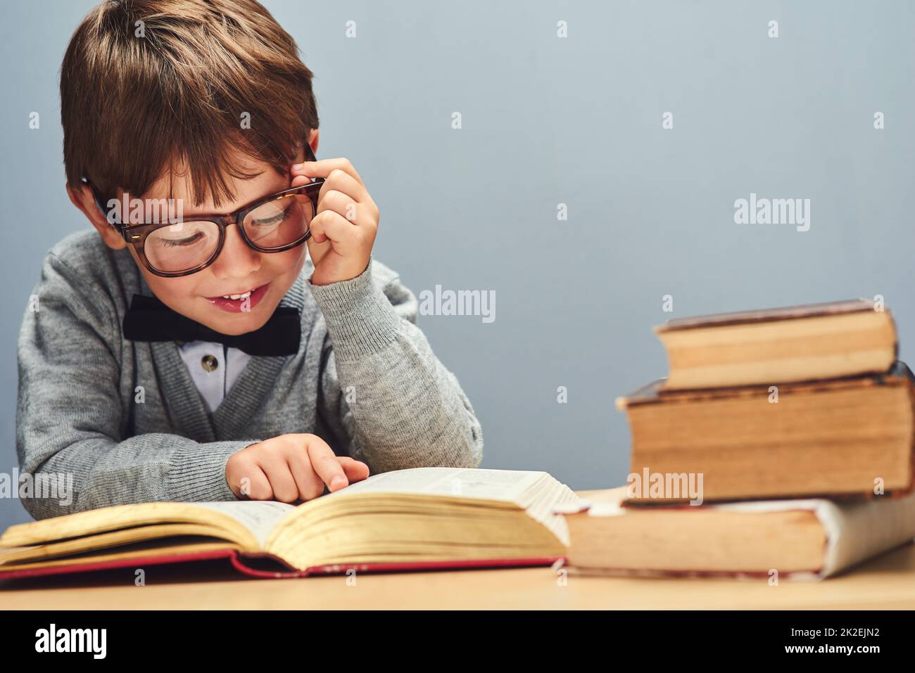 Niente cresce una mente come la conoscenza. Studio girato di un ragazzo intelligente leggere libri su uno sfondo grigio. Foto Stock