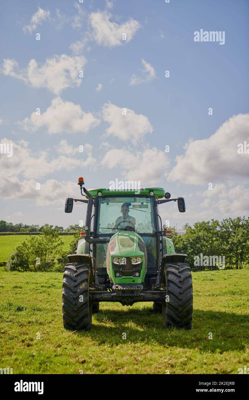 Ogni coltivatore ha bisogno di uno. Scatto completo di un trattore verde su un terreno agricolo aperto. Foto Stock