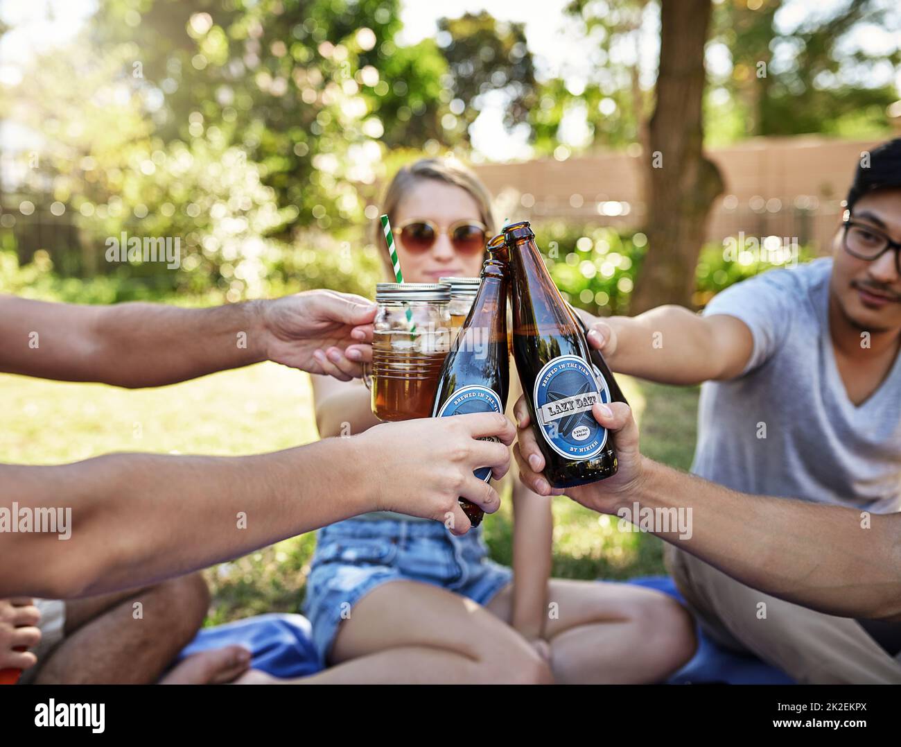 Grazie alla vita. Scatto corto di un giovane gruppo di amici che tostano mentre si gustano alcune bevande all'aperto al sole estivo. Foto Stock