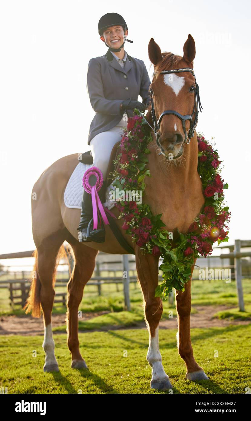 Abbiamo ottenuto la vittoria. Sparo a tutta lunghezza di una giovane ragazza attraente jockey seduta sui suoi cavalli indietro nel cerchio dei vincitori. Foto Stock