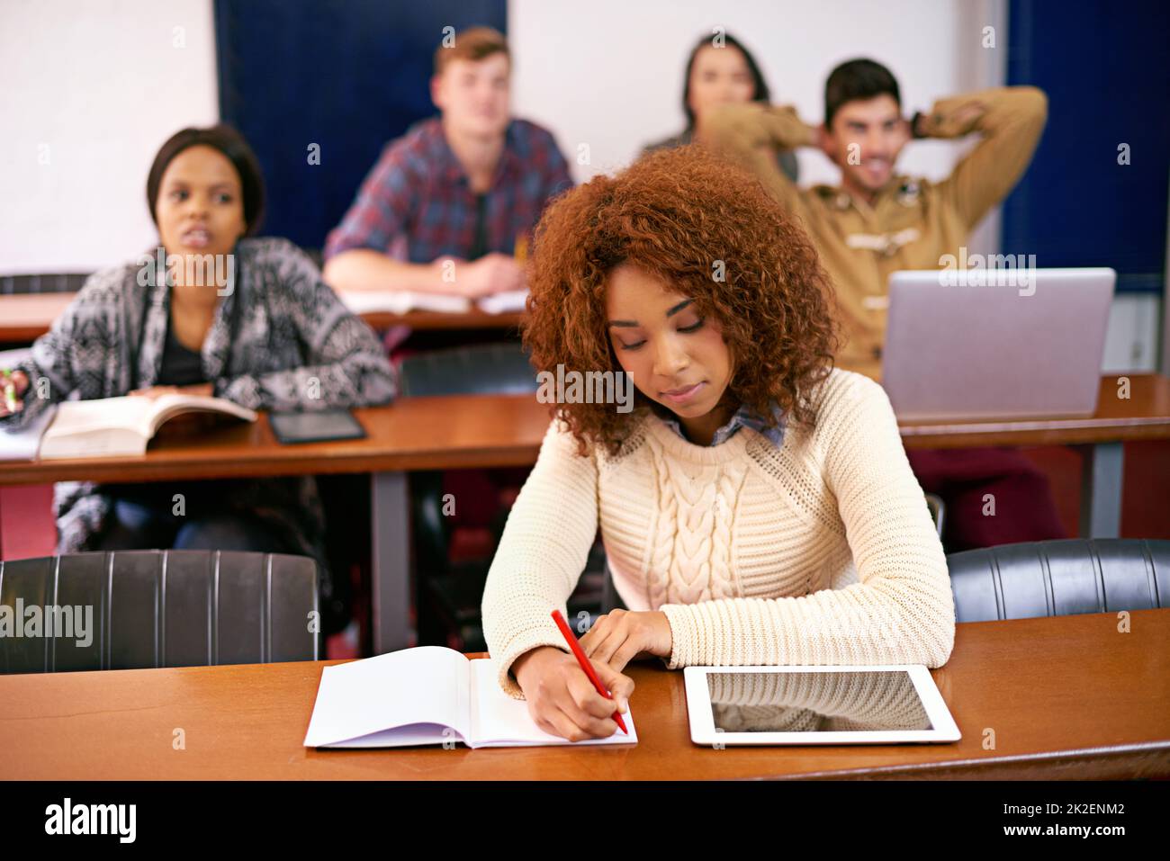 Concentrazione e determinazione a portarla al top. Uno studente che lavora alla sua scrivania in classe con un tablet digitale. Foto Stock