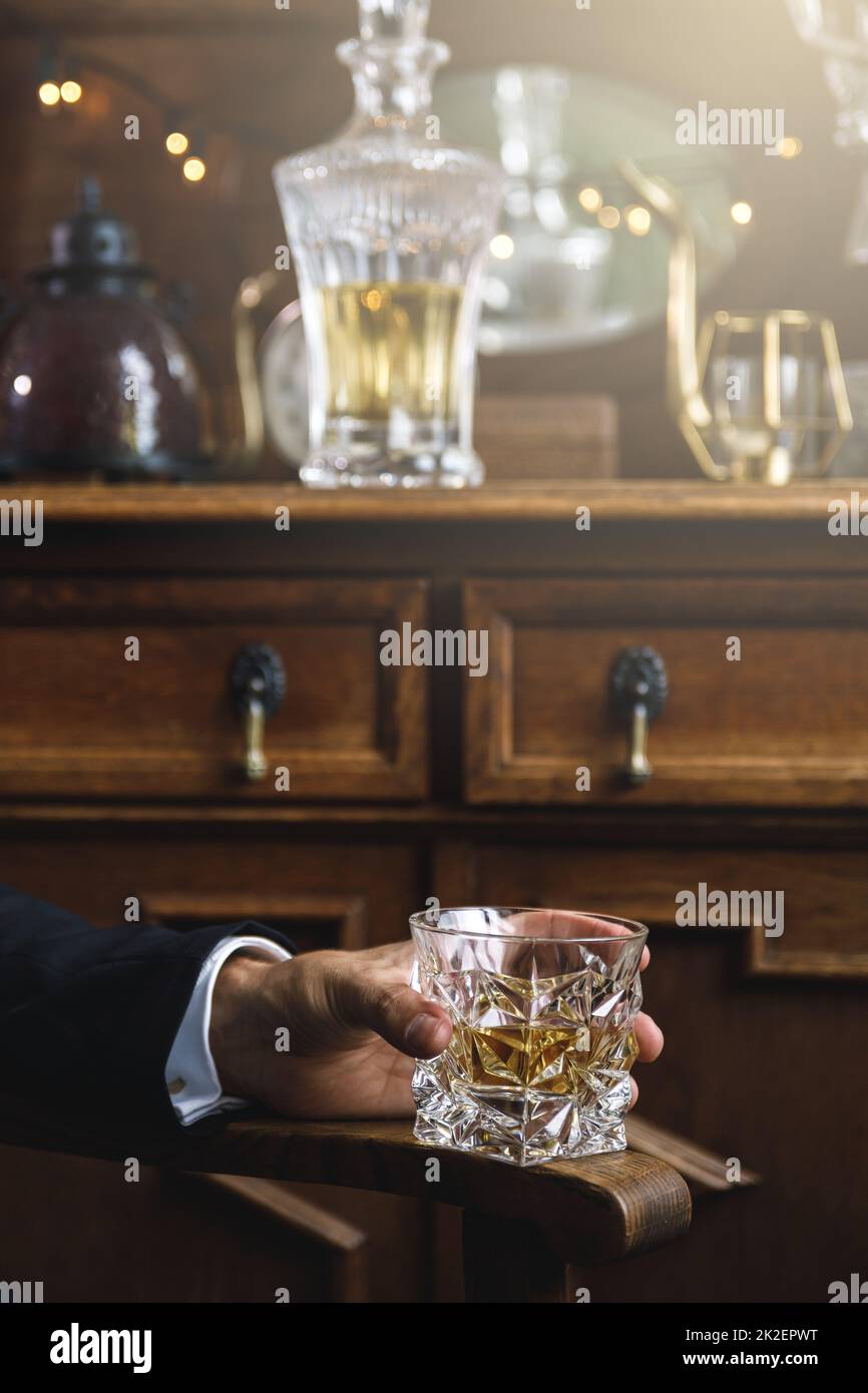 Mano maschio con un bicchiere di whiskey costoso Foto Stock