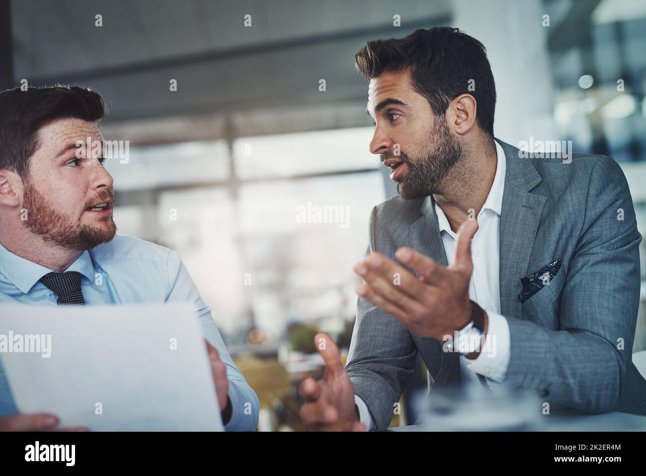 Mettere i numeri al lavoro. Scatto di due giovani uomini d'affari che passano attraverso la documentazione insieme in un ufficio moderno. Foto Stock