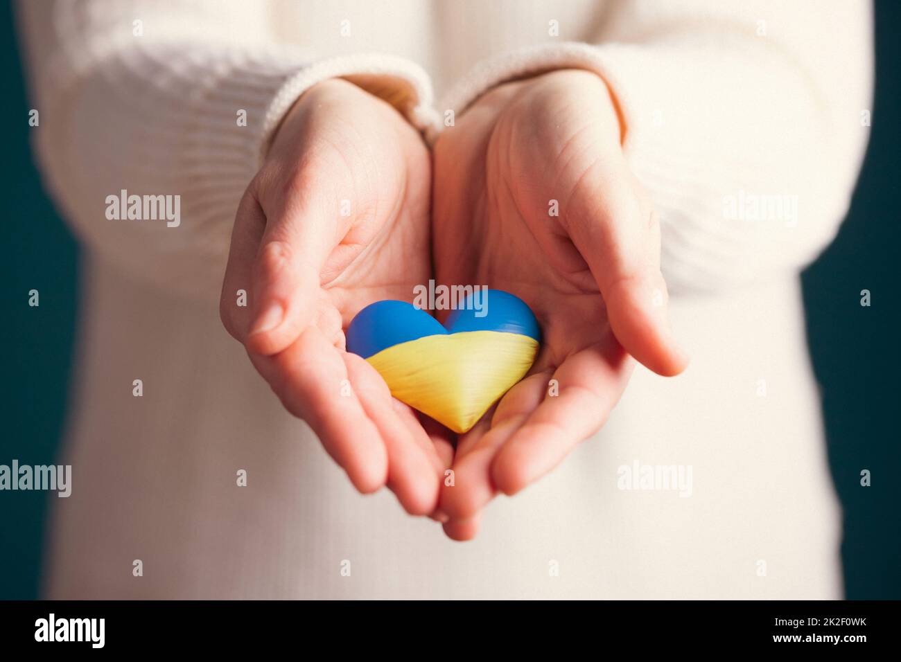 Bandiera del cuore dell'Ucraina in mani umane. Nessuna guerra, pace per l'Ucraina concetto. Foto Stock