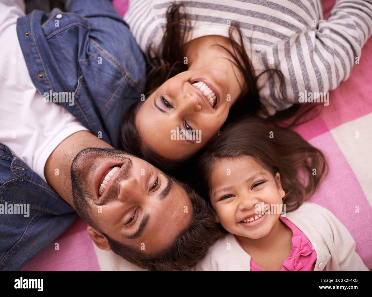 I legami familiari più forti. Ritratto ad alto angolo di una giovane famiglia felice che si trova sulle spalle a casa. Foto Stock