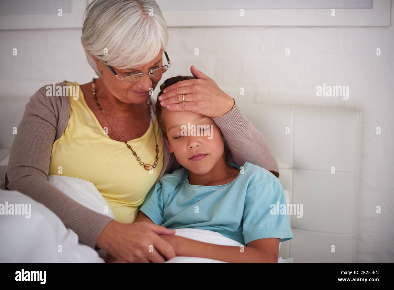 Granny si prenderà cura di voi. Shot di una nonna premurosa che si prende cura del suo nipote malato a casa. Foto Stock