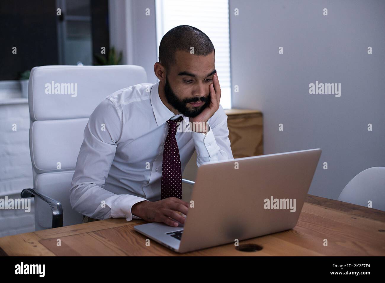 Foto di un uomo d'affari che lavora sul suo computer portatile a tarda notte. Gli uomini d'affari della vita reale hanno girato sul posto. Poiché queste posizioni sono la cosa reale e non sparato in uno studio dell'ufficio, i livelli alti di ISO sono necessari a volte per interferire il momento. L'intervallo ISO è di Foto Stock