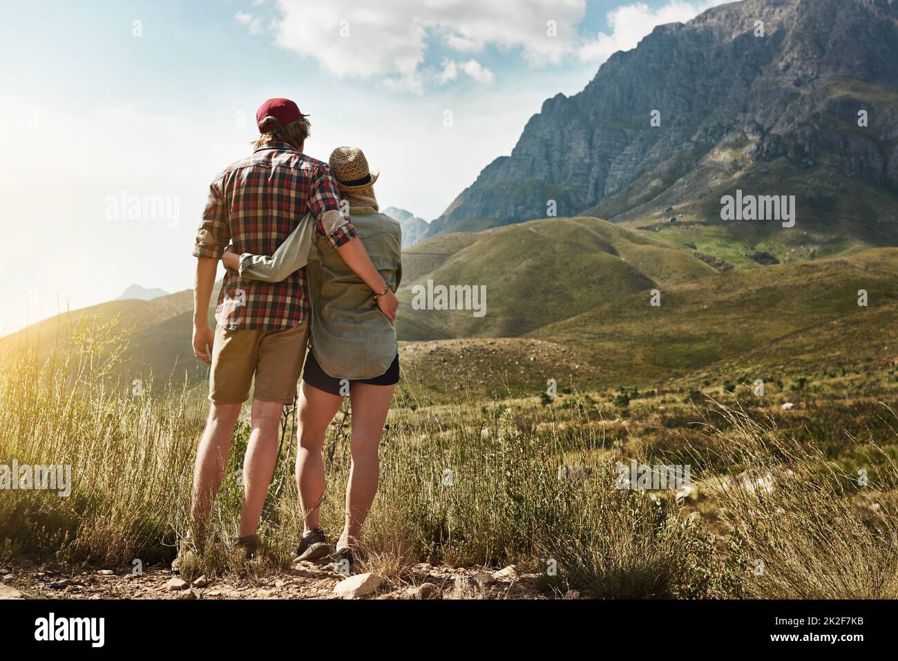 Amore ispirato alla bellezza della natura. Foto retrostenibile di una giovane coppia ammirando una vista montagnosa nella natura. Foto Stock