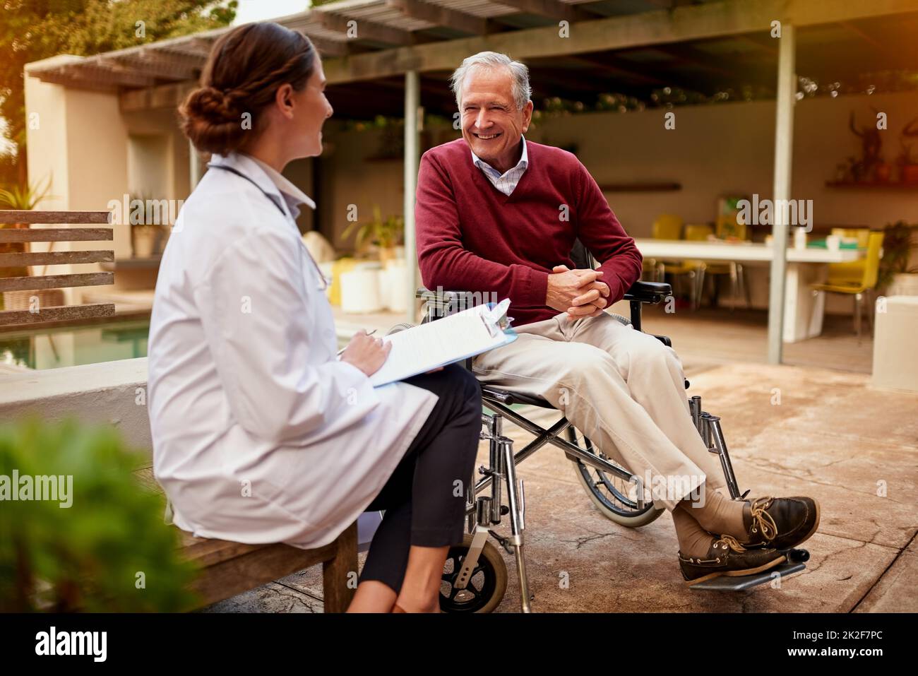 Thats grande notizia, dottor. Colpo di un medico giovane e il suo paziente anziano parlare mentre si siede fuori. Foto Stock