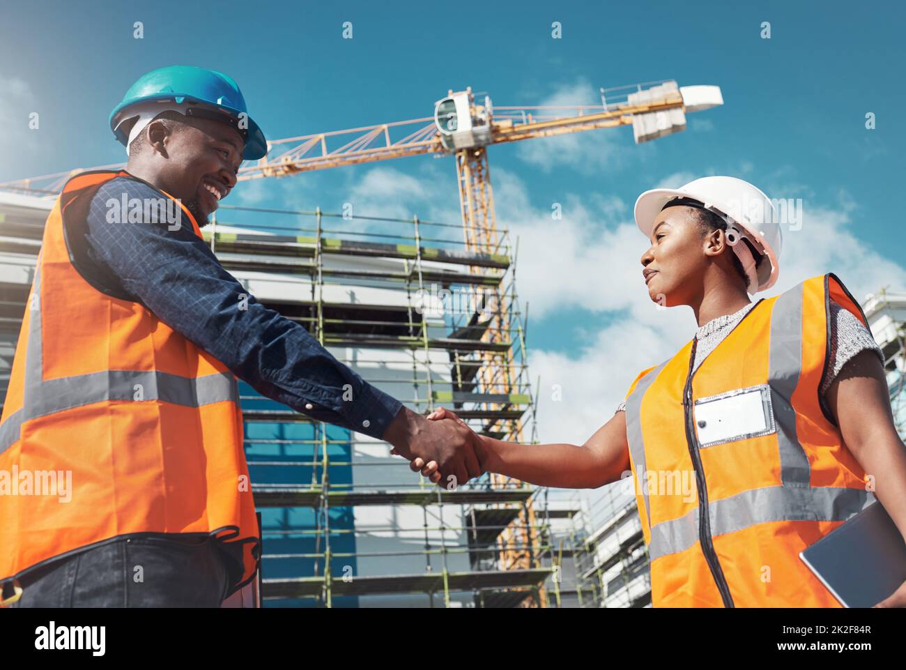 La combinazione perfetta di abilità costruttive e collaborative. Shot di due costruttori che scuotono le mani in un cantiere. Foto Stock