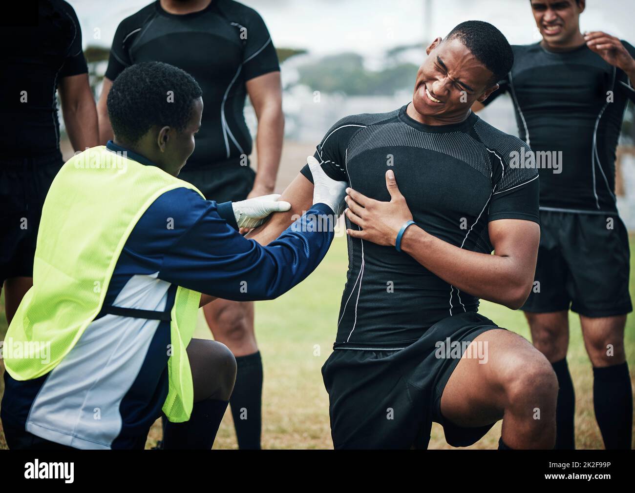 Questo fa tanto male. Scatto corto di un giovane giocatore di rugby che riceve assistenza di primo soccorso sul campo. Foto Stock