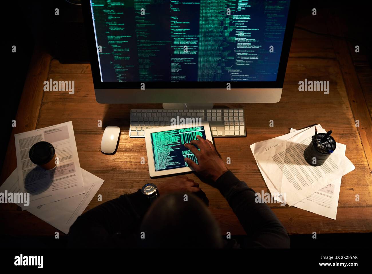 Codifica su più piattaforme. Scatto ad angolo alto di un uomo irriconoscibile che codifica sul suo tablet in ufficio. Foto Stock