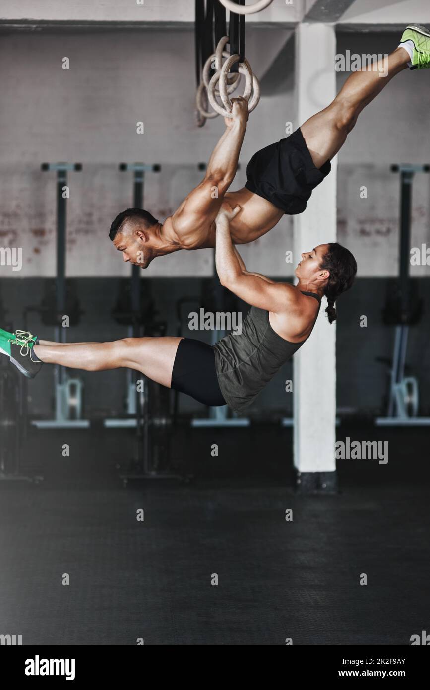 Lavorando sulla loro routine. Scatto completo di due giovani atleti che si allenano sugli anelli di ginnastica. Foto Stock