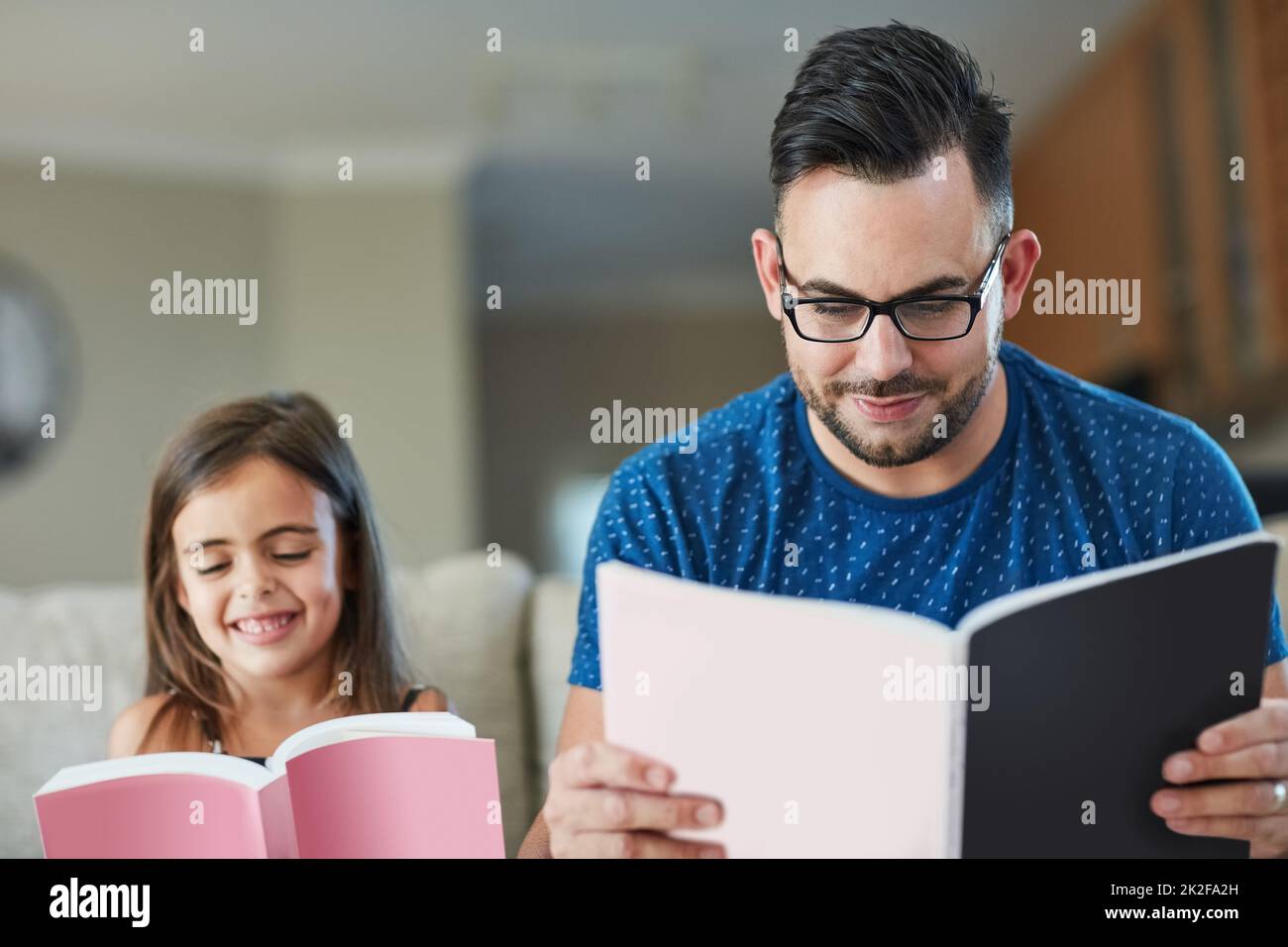 Entrambi amano ottenere accogliente e confortevole con un libro. Scatto corto di un padre una figlia che legge insieme a casa. Foto Stock