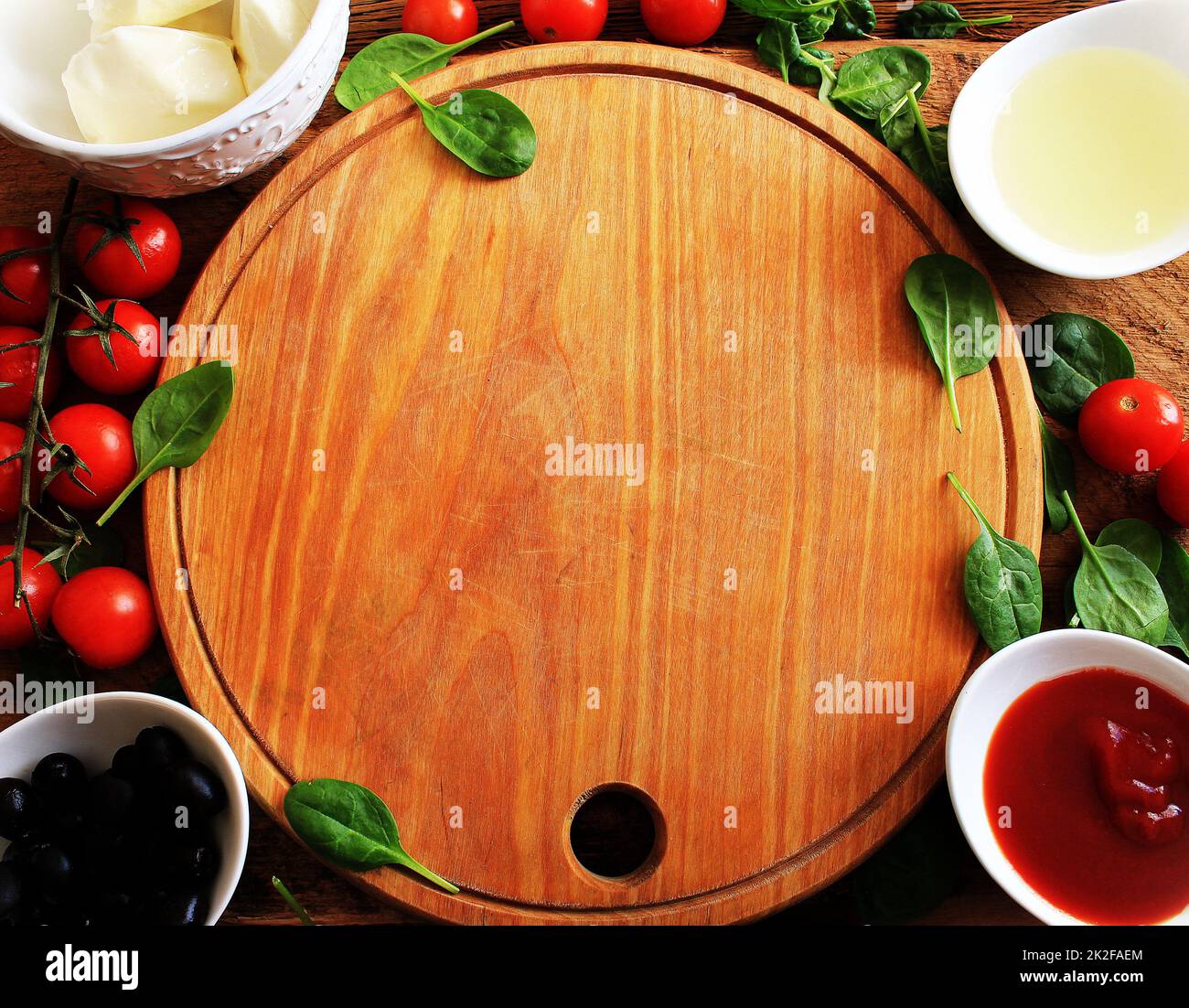 Taglio di legno con la tradizionale preparazione della pizza ingridients: Mozzarella, salsa di pomodori, basilico, olio d'oliva, formaggio, spezie. Sfondo tabella texture legno Foto Stock