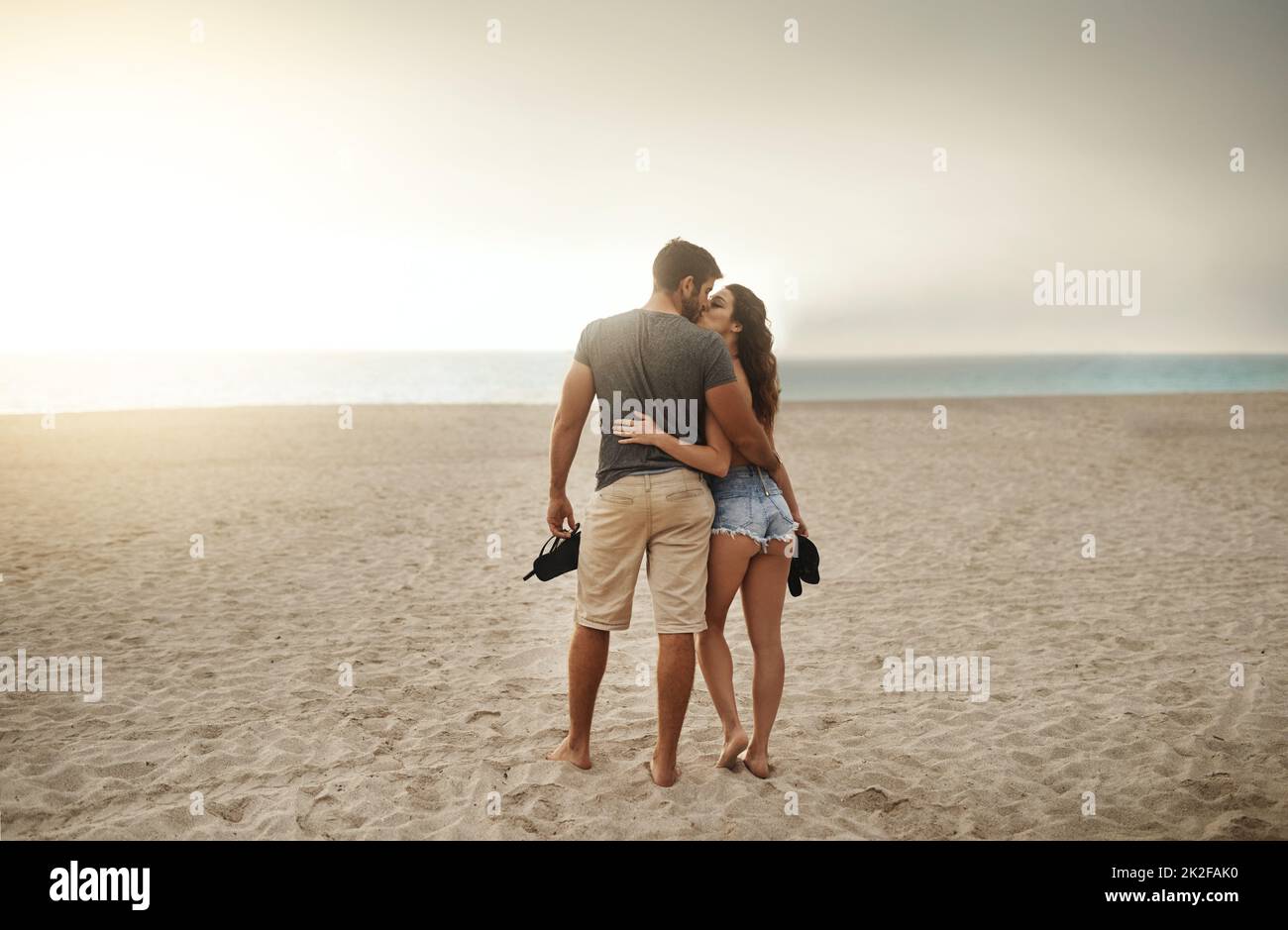 Passeggiate romantiche sul mare al tramonto. Scatto di una giovane coppia che trascorre una romantica giornata in spiaggia. Foto Stock